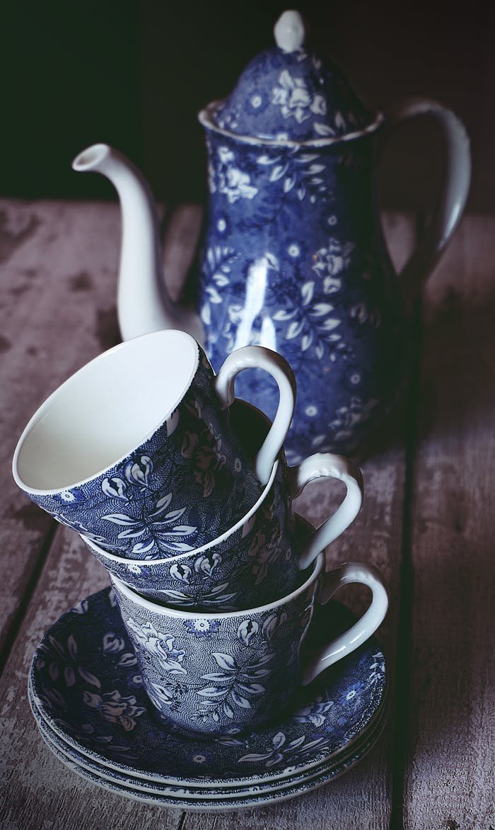Elegant blue floral porcelain tea set with teapot and teacups on a rustic table.