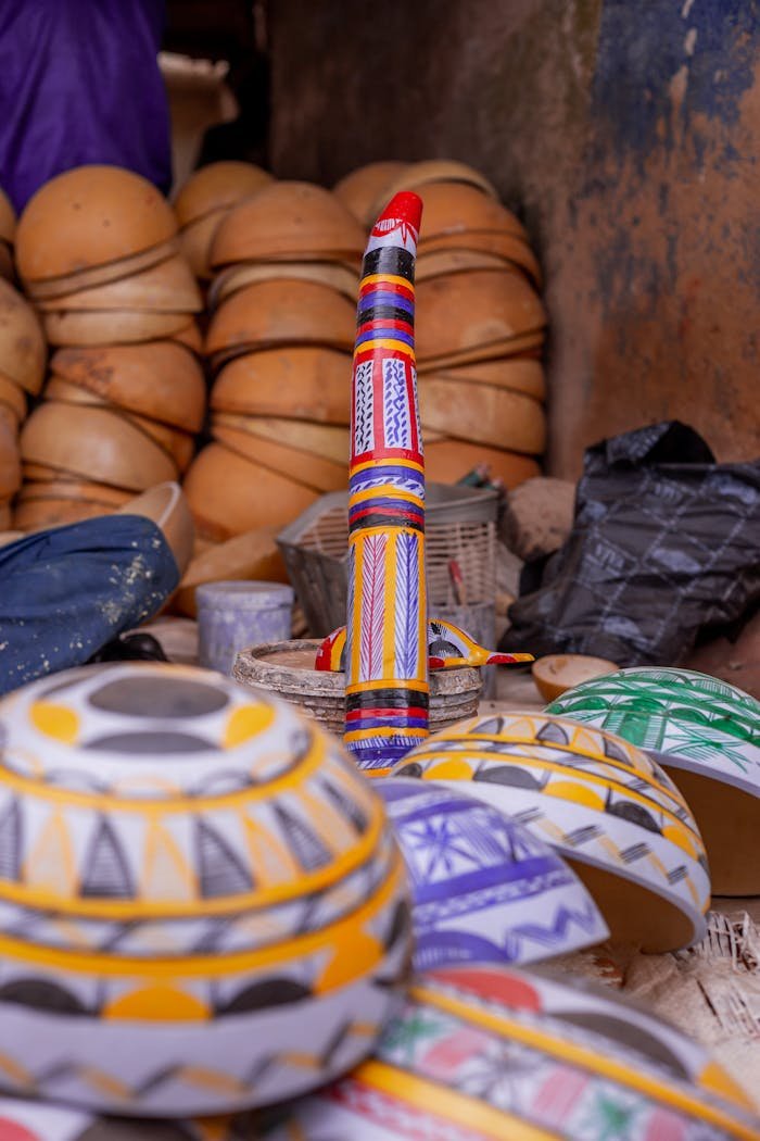 Vibrant handcrafted African pottery stacked in a traditional market setting.
